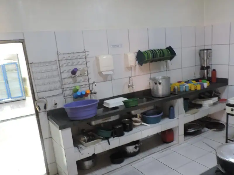 Cozinha azulejada com pia longa, fogão industrial e utensílios organizados