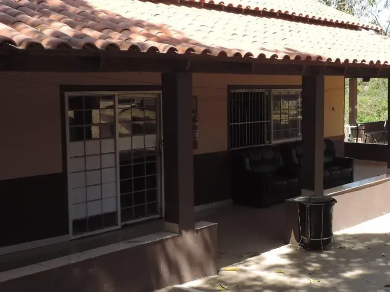 Varanda coberta com sofás de couro para convívio, junto à porta de vidro da casa